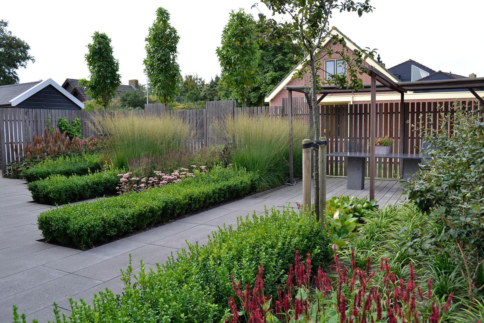 Verzorgde tuin met bloemrijke borders en strakke hagen