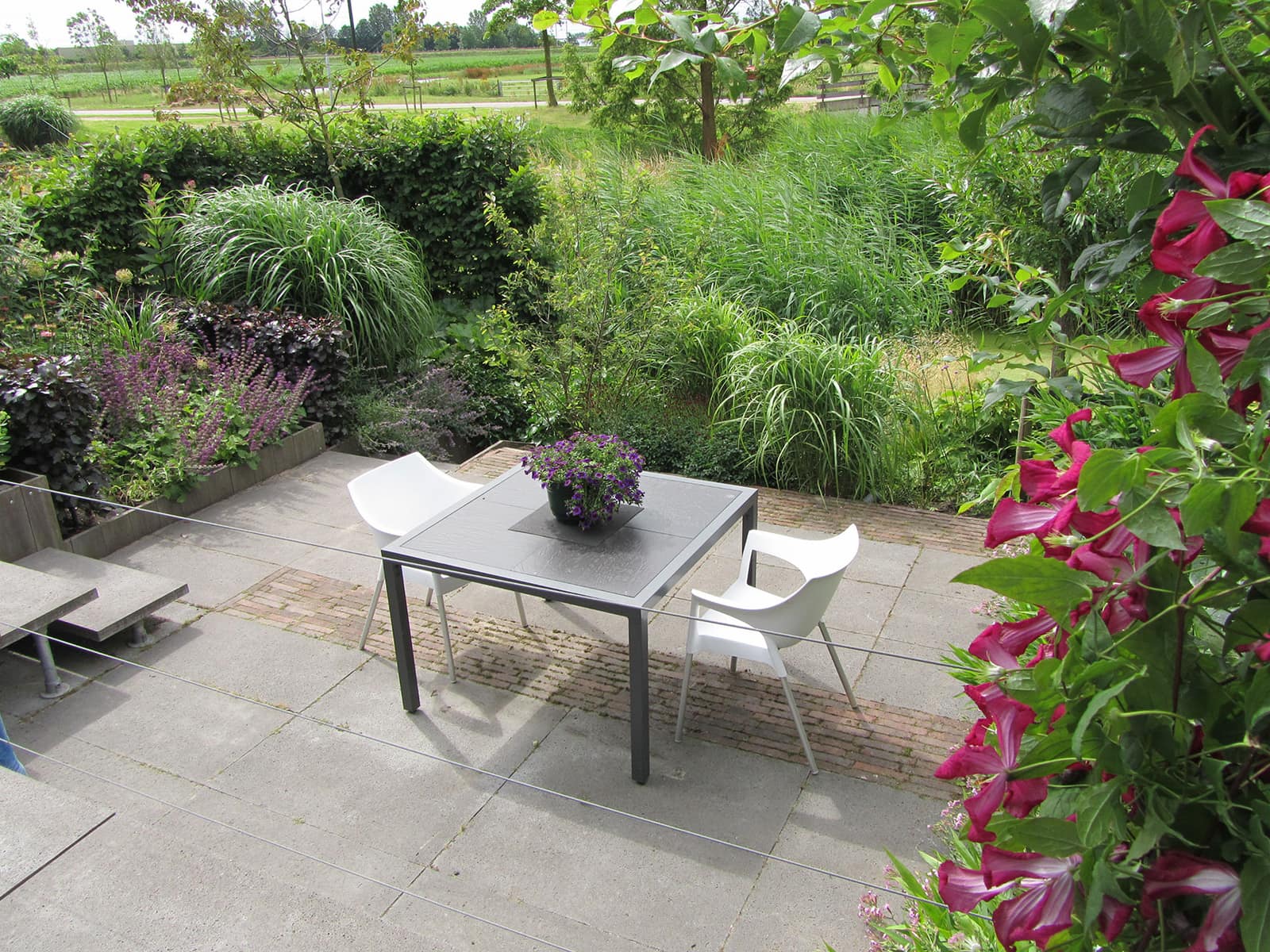 Terras met eettafel tussen volle borders